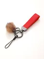 Detail shot of a red leather strap keychain with a plush brown pompom and metal rings. - Keychain Pendant / Red