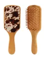 Detail of bamboo air cushion hairbrush with retro cow print back and wooden bristles. - Brown and White Cow Print Style (41294)