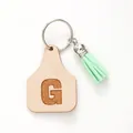 Personalized leather cow tag keychain featuring letter G with a mint green tassel charm - Letter G Style (20437)