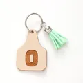 Farm style faux leather cattle tag keychain featuring letter O and a mint green tassel charm - Letter O Style (20445)
