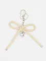 Detailed macro view of minimalist beige leather bow keychain with silver heart charm - Bowknot Charm (22426)
