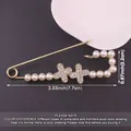 Close-up detail of metal safety pin brooch featuring decorative pearls and rhinestone crosses - Cross Pearl Style / Gold