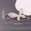 Macro detail of a gold butterfly safety pin brooch decorated with pearls and size labels - Butterfly Design / Gold