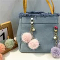 Detail view of a cute pink faux fur pom-pom keychain with a pearl charm on a denim bag - 1 Piece / Pink