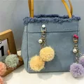 Primer plano de un lindo llavero de bola de peluche con perla en un bolso vaquero - Amarillo Brillante