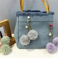 Close-up detail of fluffy plush pom-poms with pearls on decorative gold-toned bag charms - 1 Piece / Gray