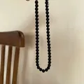 Close-up detail of a minimalist glossy black round bead necklace featuring a silver metal tag - Black Artificial Pearl Necklace / Black