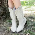 Detailed view of cream ethnic-style Western cowgirl boots with embroidery details outdoors - 36 / White