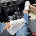 Stylish white round-toe platform sneakers for women styled with ripped blue denim jeans - 35 / White