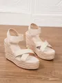 Elegantes sandalias de cuña beige para mujer con correas cruzadas y plataforma de esparto. - Albaricoque