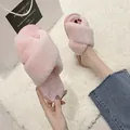 Détail des chaussons en peluche rose à brides croisées sur un tapis moelleux - Rose Éclatant