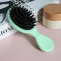 Macro view of a mint green boar bristle cushion brush on a soft pink background. - Green