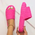 Detailed macro view of vibrant hot pink platform plush slippers with embossed strap - Rose Red