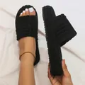 Close-up view of black embossed fuzzy slides with thick sole and plush texture. - 35 / Black