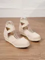 Vista detallada de las elegantes sandalias de cuña beige para mujer en suelo madera. - Albaricoque