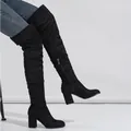 Detailed close-up of black suede over-the-knee boots with chunky heels on a model. - 38 / Black