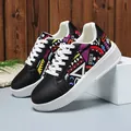 Close-up of low-top sneakers featuring vibrant geometric tribal patterns on a white base. - 36 / Black