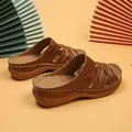 Detail view of brown wedge sandals with elegant hollow-out floral patterns and crossover straps - 36 / Tan