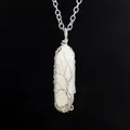 Close-up of wire-wrapped tree of life pendant on a white hexagonal crystal pillar. - Small White Crystal