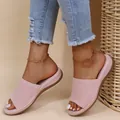 Detailed view of women's pink knit platform sandals worn with denim jeans on beach - Light Pink