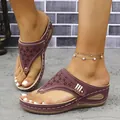 Primer plano de sandalias de cuña color granate con patrones láser y remaches dorados - Púrpura