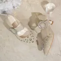 Close-up detail of pointed-toe denim pumps with rhinestone buckle and silver studs - 36 / Apricot