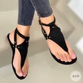 Sandales plates à entre-doigts noires pour femmes avec bride à la cheville portées - Noir