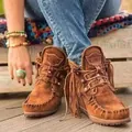 Dettaglio di stivaletti scamosciati marroni con frange boho e cuciture stile mocassino - Marrone