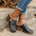 Detail of black vintage clogs with floral cutouts and metallic buckle on wooden heel. - 36 / Black