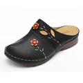 Detail view of black women's wedge slippers with decorative orange flowers and leaf patterns - Black