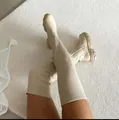 Detailed view of beige over-the-knee fly-knit boots with chunky lug sole on white rug - 36 / Beige