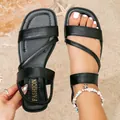 Detailed view of black flat Roman sandals on sand with stylish seashell anklet - 35 / Black