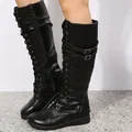 Close-up detail of black high-top lace-up boots with multiple buckle straps and zipper. - Black