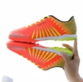 Vibrant orange and yellow youth soccer shoes with TF turf cleats and MEDARON branding - Orange