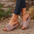 Detail of mauve wedge sandals with flower decor and laser-cut patterns on a model - Pink