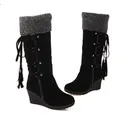Detail view of black suede wedge boots with grey fur trim and decorative side tassels. - 35 / Black
