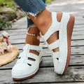 Detailed side view of white women's hollow-out wedge sandals on a wooden plank path - 36 / White