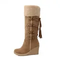Side view of brown suede knee-high boots with sherpa cuff, tassels, and wedge heels. - 35 / Brown
