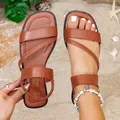 Close-up detail of brown Roman flat sandals with cross straps on beach sand background - 35 / Brown