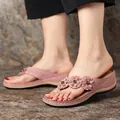 Close-up detail of retro dusty pink wedge flip-flops featuring three decorative flowers. - 36 / Pink