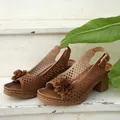Gros plan de sandales compensées marron ajourées avec décoration de fleurs élégante - Beige