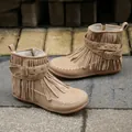 Detailed macro view of camel suede flat ankle boots featuring fringe and rivet buckles - 35 / Off White