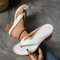 Detailed view of white flip-flop sandals with chunky heels and elegant stitching. - 36 / White