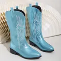 Vue détaillée de la surface bleu métallisé et de la broderie blanche des bottes de cowboy - Bleu clair