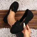 Detailed close-up of black suede loafers featuring decorative tassels and stitching - Black
