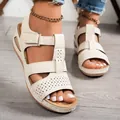 Close-up of cream wedge sandals with velcro straps and laser-cut detail on feet. - 36 / White