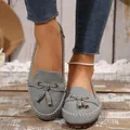 Gros plan détaillé de mocassins en daim gris avec pompons élégants et coutures blanches - Gris