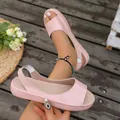 Detail view of pink peep-toe flat sandals with elastic back strap on wooden deck - Pink