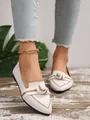 Detail shot of white fly-knit pointed flats with decorative bow and gold trim. - White