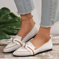 Close-up of white pointed-toe flats with bow detail and tan piping worn by model - 36 / White